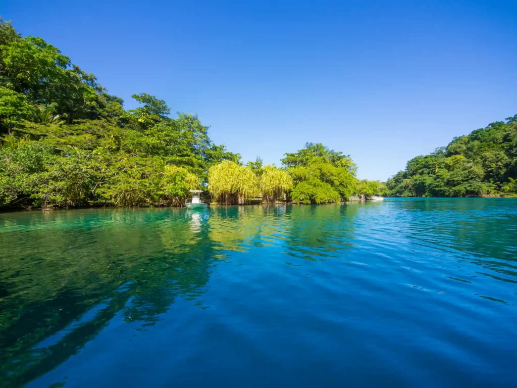 The Blue Lagoon in Portland, Jamaica, a serene, deep blue natural lagoon surrounded by lush tropical vegetation and known for its calm, mineral-rich waters.