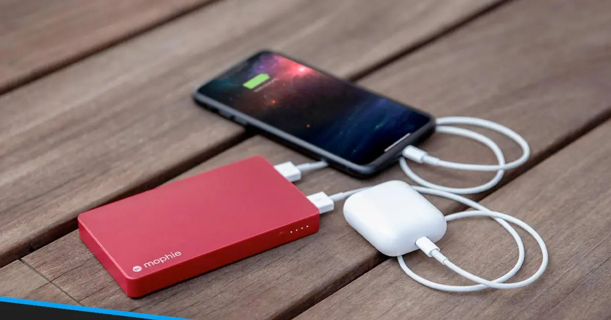 Red power bank charging smartphone on wood